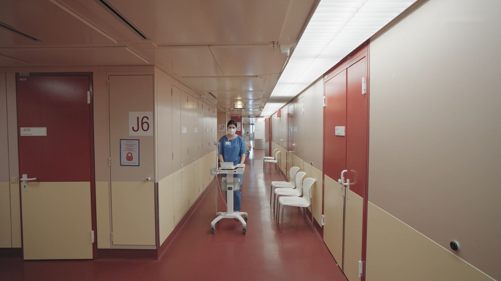 Pflegerin schiebt einen Gerätewagen durch den Gang J6