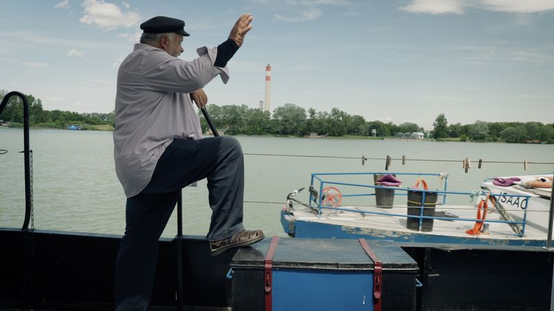 Er winkt vom Deck einem vorbeifahrenden Boot zu
